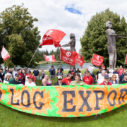 Ralliers hold a large sign reading "Ban Raw Log Exports" in Port Alberni