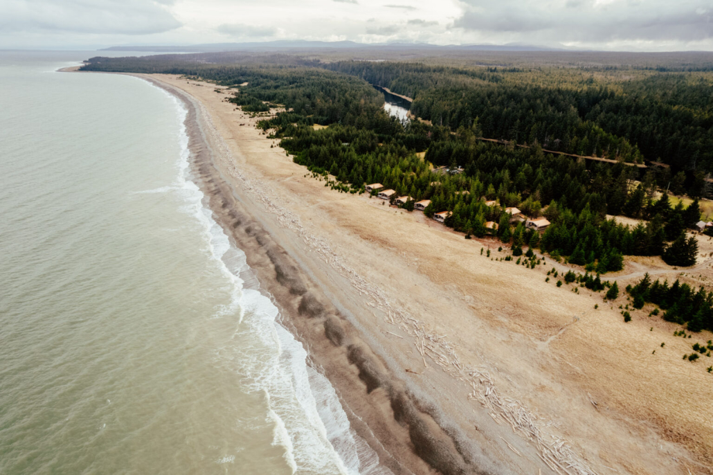 A long, expanding beach dotted with Haida House at Tllaal oceanside cabins on Haida Gwaii.