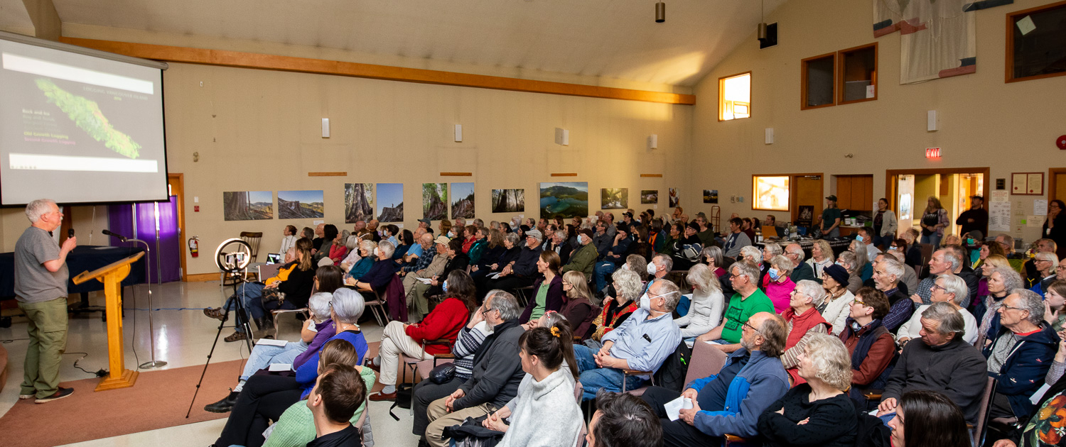 About 200 people listening intently as renowned forest ecologist Andy MacKinnon presents about old-growth forests vs. second-growth tree plantations